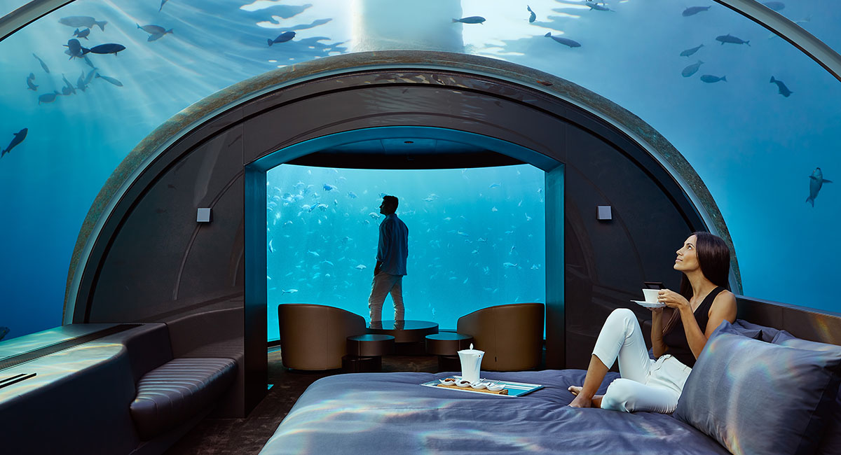 man in under the sea hotel room looking out the window